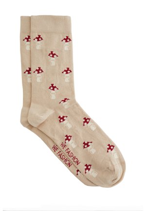 Beige Socken mit einem wiederholten Muster aus roten und weißen gepunkteten Pilzen, mit dem Schriftzug "WE FASHION" im Bereich der Zehen.