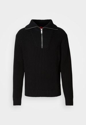Black ribbed sweater with a high collar and short zipper. Features textured fabric and fitted cuffs, providing a structured silhouette.