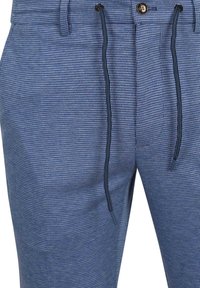 Modré kostkované kalhoty s strukturovanou tkaninou, vybavené knoflíkovým zapínáním a stahovacími šňůrkami v pase. Ozdobené kontrastními tmavými stahovacími šňůrkami.