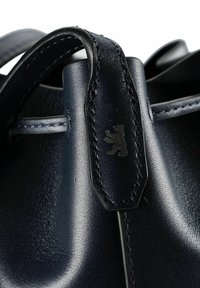 Borsa in pelle blu navy con texture liscia, caratterizzata da cuciture nere e un logo orso su un'etichetta. I manici sono ad anello e dal design robusto.