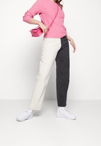 Ljusrosa ribbad tröja, i kombination med tvåfärgade byxor (vita och mörkgrå). Vita sneakers och en liten rosa axelväska fulländar outfiten.