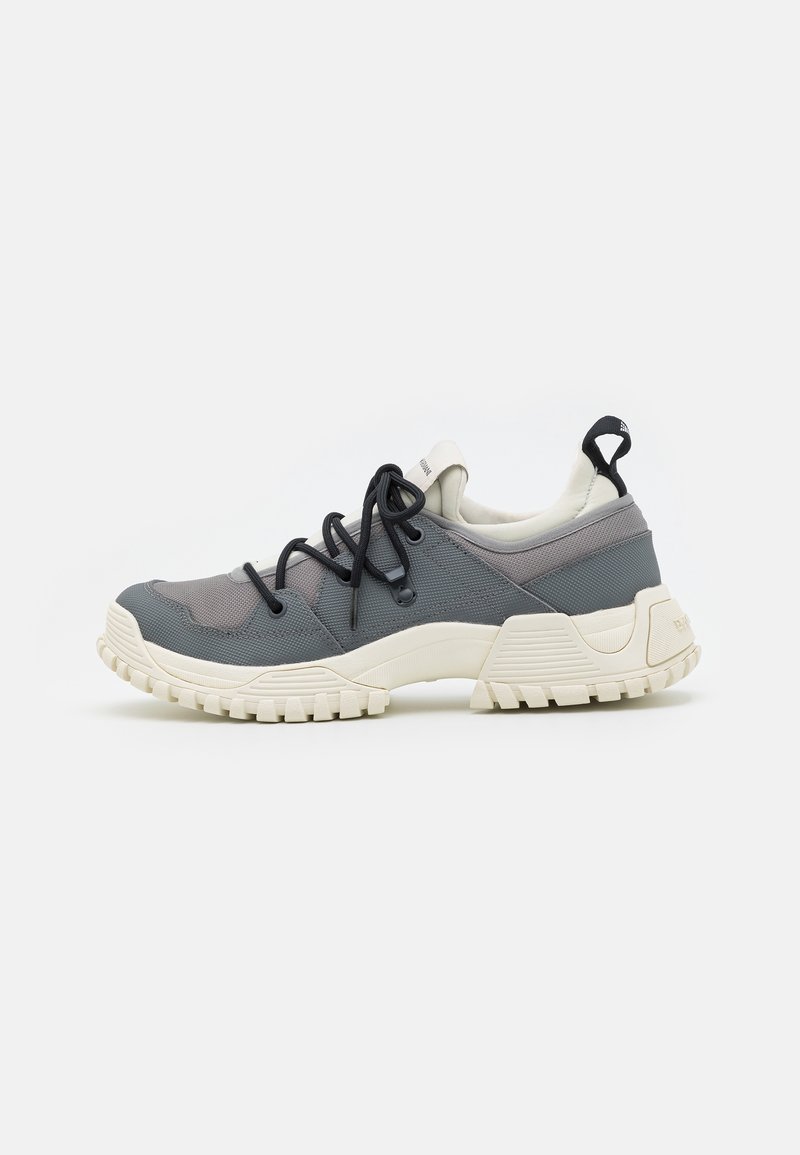 Baskets basses gris et blanches avec semelle épaisse, lacets noirs, empeigne en mesh, et languette à l'arrière, vues de profil.