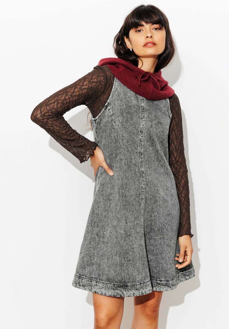 Robe en denim grise de forme évasée, dotée d'une capuche en tricot bordeaux foncé et de longues manches en dentelle. Détails de couture remarquables le long de l'ourlet.