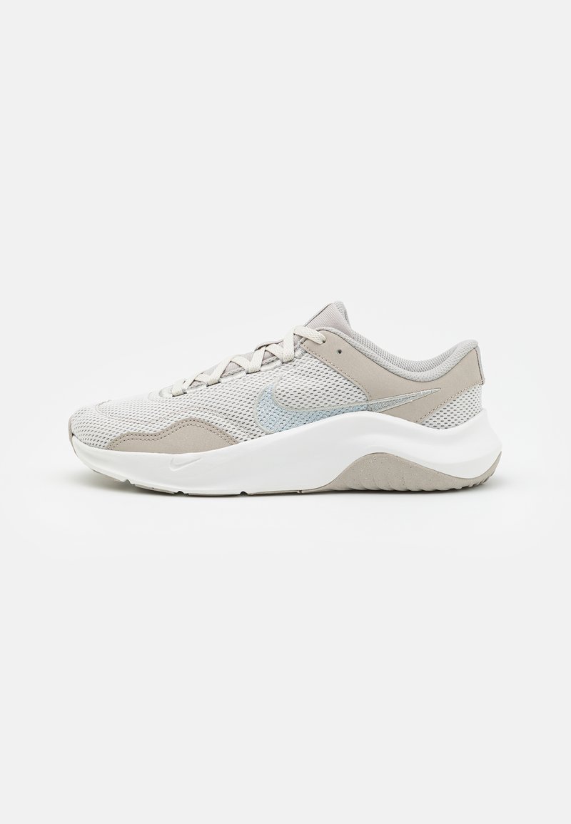 Light grey athletic shoe with mesh upper, smooth suede accents, white rubber sole, and a subtle reflective logo. Streamlined design.