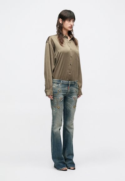 Dlhá rukávová blúzka z olivovo zelenej saténovej látky s prednými gombíkmi, doplnená svetlomodrými rozšírenými džínsami zdobenými farebnými kameňmi a vzormi z korálok.