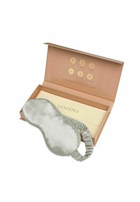 Hedvábná noční maska ve světle šedé barvě s elastickým páskem, umístěná uvnitř béžové krabičky s zlatými ikonami a názvem značky "LENOITES."