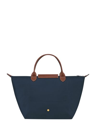 Navy blue tote bag made of fabric with brown leather handles and accents, featuring a front pocket and zipper closure.