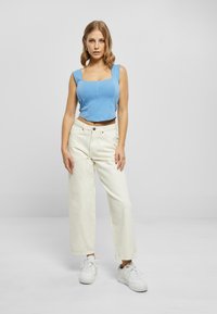 Lys blå kortermet tank topp med firkantet utringning, kombinert med off-white vide jeans og hvite sneakers, med en avslappet passform.