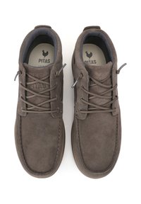 Zapatos de ante marrón con un diseño de perfil bajo, que presentan cordones tradicionales, un cuello acolchado y una suela de goma texturizada. Logotipo de la marca visible en el interior.