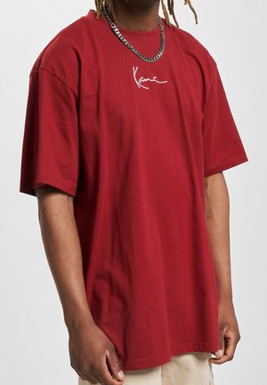 Rotes Baumwoll-T-Shirt mit lockerer Passform, kurzen Ärmeln und einem weißen, geschwungenen Logo auf der Brust. Es hat einen runden Halsausschnitt und ein schlichtes Design.