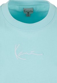 Light blue sweatshirt with ribbed collar, featuring white embroidered text. Soft fabric and casual design for comfortable wear.