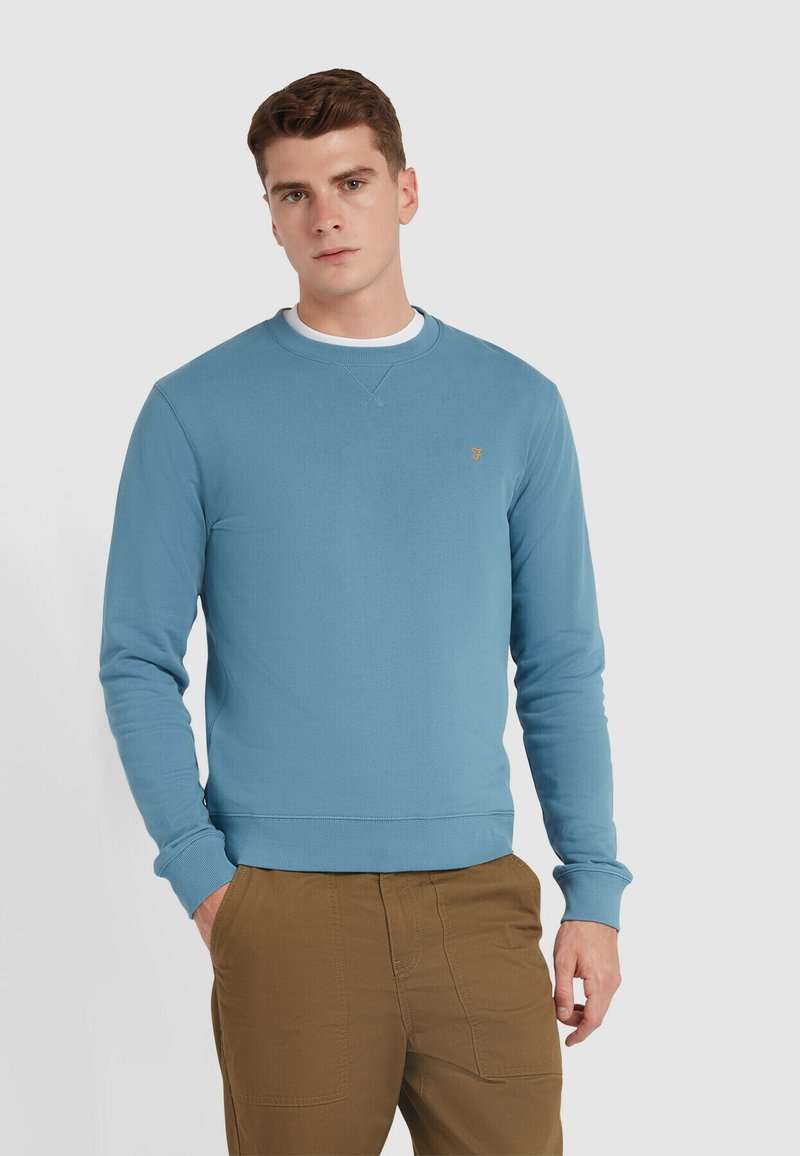 Hellblaues Sweatshirt mit langen Ärmeln und einem gerippten Rundhalskragen. Verfügt über ein kleines gesticktes Logo auf der Brust und einen gerippten Saum.