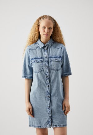 Vestido de camisa de mezclilla en azul claro, con mangas cortas, cierre de botones, dos bolsillos frontales y un ajuste ligeramente holgado.