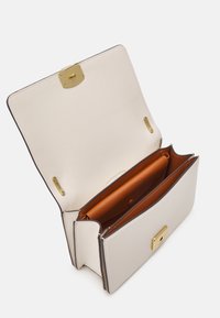 Borsa a mano in pelle color crema chiaro con finiture in oro. Interno con scomparti in pelle marrone e chiusura a scatto. Design strutturato, stile aperto.