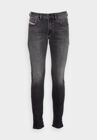 Jeans skinny negros de denim con un ligero desvanecimiento. Cuenta con cinco bolsillos, pasadores para cinturón y detalles de hardware metálico. Diseño clásico.