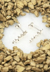 Boucles d'oreilles en argent en forme d'étoile avec un design texturé. Les étoiles varient en taille et sont disposées en ligne diagonale.