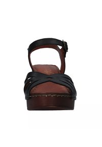 Sandalo in pelle nera con design a fascia intagliata, soletta marrone e tacco in legno basso. Presenta una cinghia alla caviglia regolabile con fibbia.