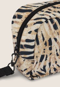 Borsa in tessuto rettangolare con base color sabbia, caratterizzata da un motivo astratto in nero e marrone. Chiusura con cerniera nera e dettagli in metallo, tra cui un moschettone.