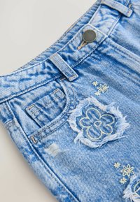 Shorts en denim de couleur bleu clair avec un ourlet effiloché, broderie florale décorative et une petite poche ; bouton en métal et passants de ceinture visibles.