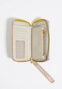 Billetera gris claro con interior amarillo, que cuenta con múltiples compartimentos para tarjetas, un bolsillo con cremallera para monedas y una correa de tela con el nombre de la marca.