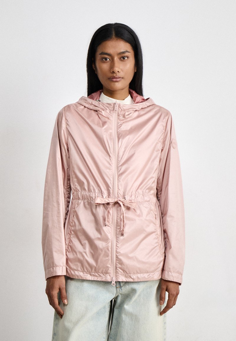 Chaqueta rosa claro con capucha, cintura ajustada, cierre de cremallera y mangas largas. Tejido liso y brillante con un corte holgado.