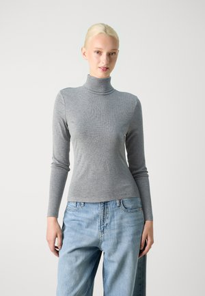 Grå langermet genser med høy hals og en tettsittende design og ribbestruktur, kombinert med lyseblå baggy jeans. Enkel og moderne silhuett.