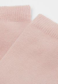 Helle rosa Baumwollsocken mit geripptem Bündchen, glatter Textur und gleichmäßigem Strickmuster. Zwei Socken, die zueinander geneigt sind.