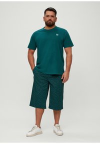 Groene katoenen T-shirt en gestreepte shorts met witte stippen. Met een relaxed fit is de outfit gecombineerd met witte sneakers.