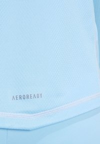 Lichtblauw sporttop met honingraatstructuur, voorzien van "AEROREADY" branding in grijs, aangevuld met contrasterende stikdetails.
