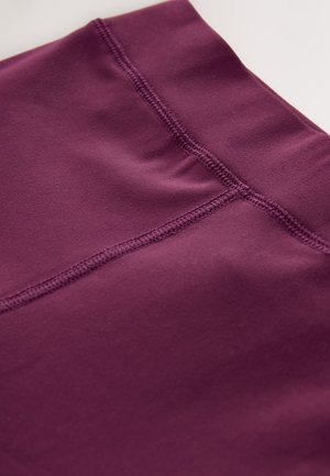 Tessuto sportivo di colore viola scuro con una texture liscia, caratterizzato da dettagli di cuciture flatlock. Il design enfatizza un aspetto senza cuciture.