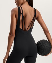 Fekete sportos testre simuló trikó mély V-kivágással és több vékony pánttal. Egy textúrált fekete edzőlabdával együtt látható.