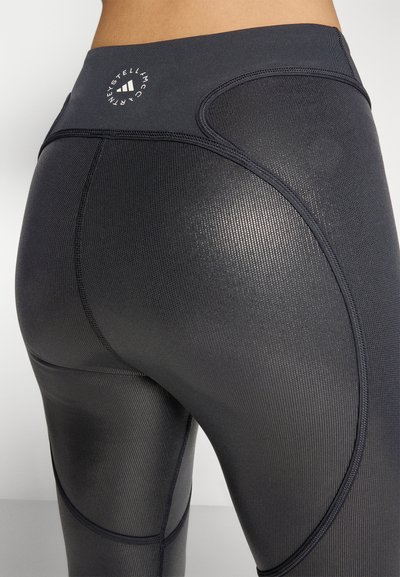 Magas derekú fekete leggings texturált, bordás mintával. Kör alakú logóval és jól látható varrással a hátsó részen.