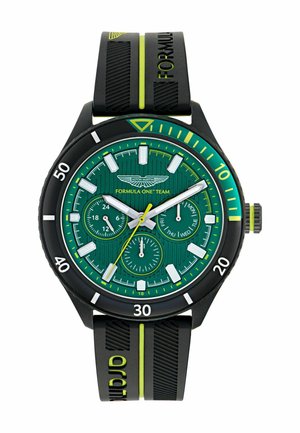 Aston Martin Formel 1 ur med en grøn struktureret urskive, sort gummirem med gule accenter og hvide timemarkeringer.