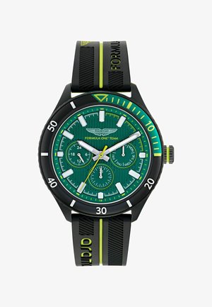 Aston Martin formulės vieneto laikrodis, turintis žalią tekstūruotą ciferblatą, juodą gumos dirželį su geltonais akcentais ir baltais valandų ženklais.