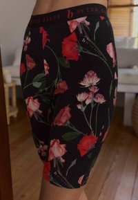 Zwarte short met een bloemenpatroon van rode rozen en roze bloemen. Zacht materiaal en een gebrandmerkt elastiek. Lengte tot halverwege de bovenbenen.
