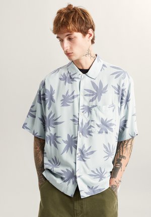Kurzarm-Hemd mit Knopfleiste in Hellblau, verziert mit großen, dunkelblauen Blättermustern. Verfügt über eine Brusttasche und einen lässigen Schnitt.