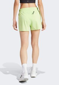 Light green athletic shorts with an elastic waistband and a small zippered pocket, designed for comfort and mobility during activity.