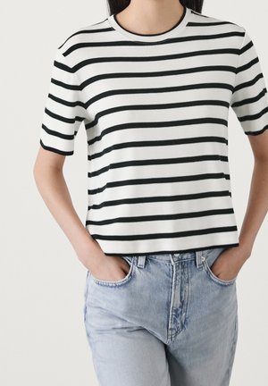 Biały T-shirt z czarnymi poziomymi paskami, krótkimi rękawami i okrągłym dekoltem, zestawiony z jasnoniebieskimi dżinsami.