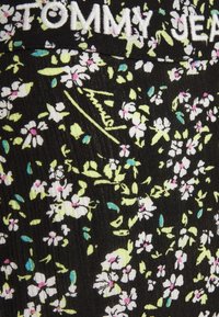 Tessuto nero con motivo floreale con fiori bianchi, rosa e blu. Il logo "TOMMY JEANS" è ricamato in vita.