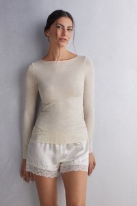 Langærmet beige top lavet af letvægtsstof, parret med cremede satin shorts med blondekant i kanten. Glat tekstur hele vejen igennem.