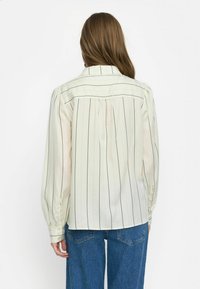 Lange mouwen, crèmekleurig shirt met verticale zwarte strepen, met een zachte stof, knoopmanchetten en een yoke aan de achterkant.