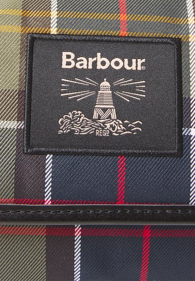 Patch du logo Barbour avec un phare et des vagues sur un tissu tartan multicolore avec des rayures rouges, bleues, vertes, jaunes et blanches.