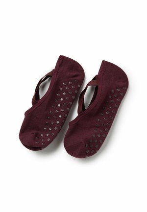 Paar dunkelrote Slip-On-Ballettsöckchen mit rutschfesten Sohlen und elastischen Kreuzriemen, auf weißem Hintergrund gezeigt.