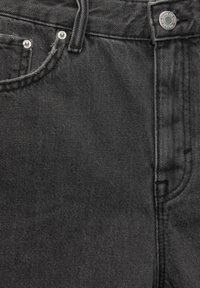 Svarta denimjeans med en klassisk femfickdesign, metallkomponenter och en texturerad yta. Sytt detaljer längs sömmarna.