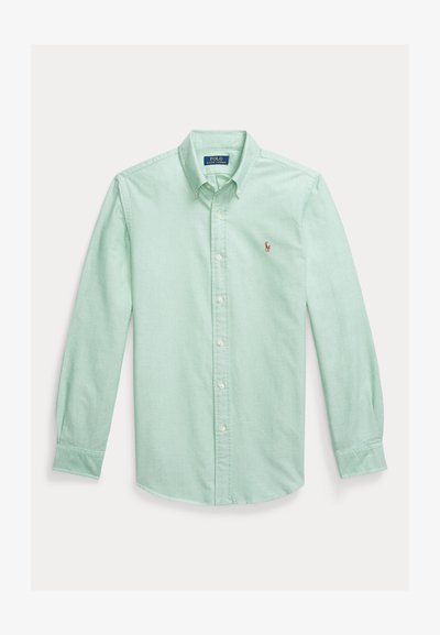 Šviesiai žalia medvilninė marškiniai su sagomis, ilgomis rankovėmis, smailia apykakle ir mažyliu siuvinėtu logotipu kairiajame krūtinės plote.