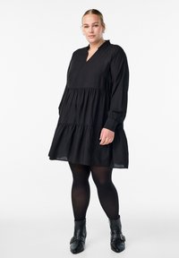 Must have mustruudiga kergest kangast must kihtkleit, millel on V-kaelus ja pikad varrukad. Kanda mustade sukkpükste ja kaunistuste ning nööridega ankle boots'idega.