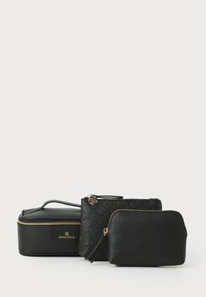 Três necessaires negras de formas e tamanhos variados, apresentando materiais lisos e texturizados, fechos dourados e um detalhe floral.