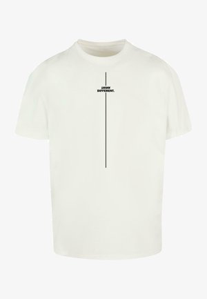 Hvit bomulls t-skjorte med rund hals. Har en vertikal svart linje og setningen "TANK ANNERLEDES." trykt sentralt.