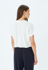 Korte witte t-shirt met korte mouwen. Heeft een ronde halslijn en een eenvoudig ontwerp, gemaakt van zachte katoen.