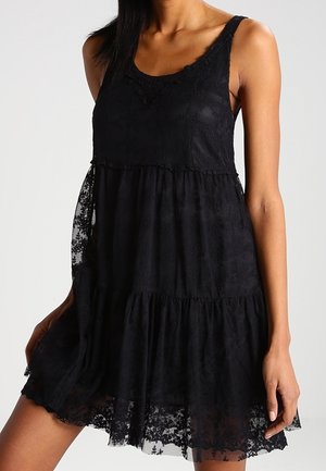 Vestido de encaje negro en capas con diseño sin mangas, que presenta patrones florales, un escote redondo y una silueta fluida.